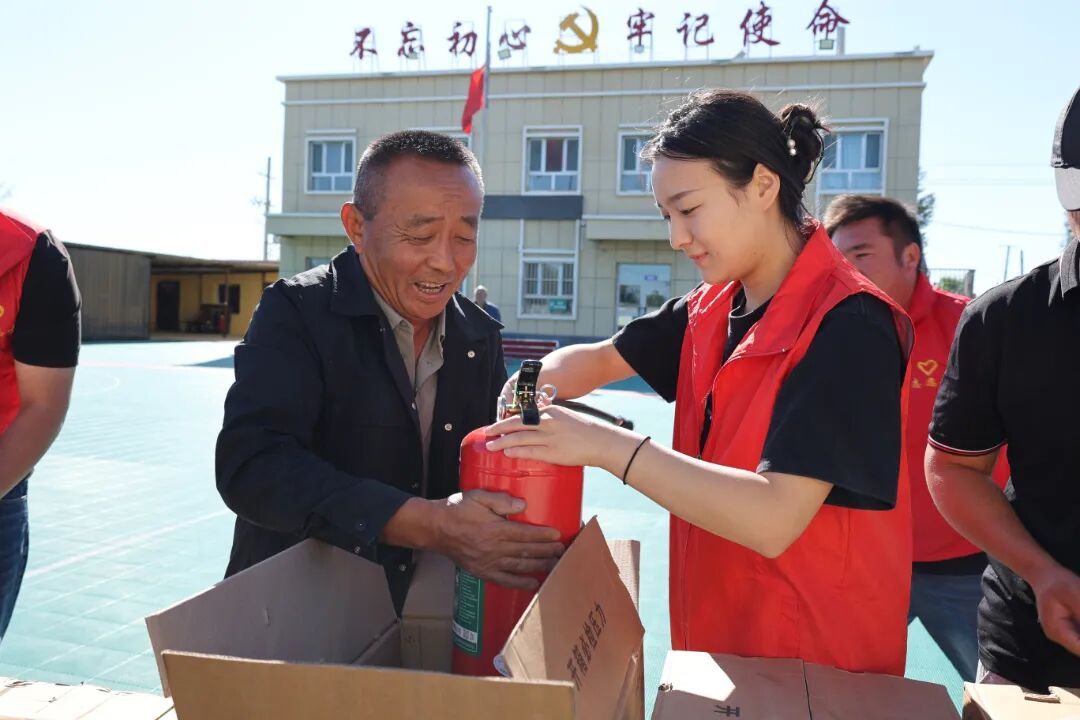 四道河子镇党员志愿者为在场群众分发灭火器.jpg